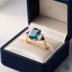 Elegant Teal Blue Emerald-Cut Ring with Gold Band and Side Stones